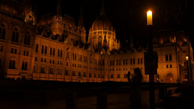 Souvenir photos of parliament in hungary. A view of female takes a photo for her collection of budapest parliament during night time.