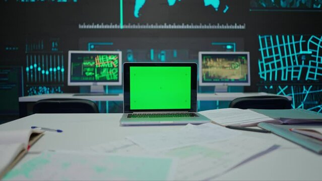 Computer at the desk in control center. Military headquarters surveillance office, laptop standing on the table with chroma key green screen.