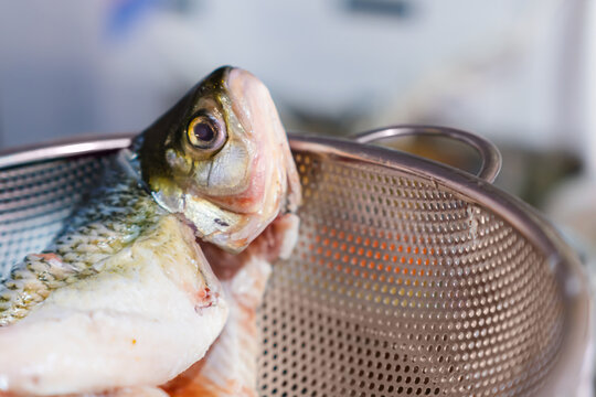 Raw unseasoned bocachico fish on metal strainer, seafood food preparation