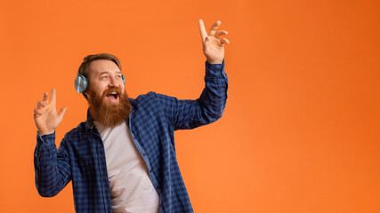 Emotional redhaired bearded man in headphones singing favorite song, studio