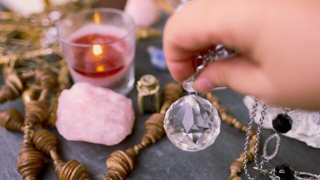 female fortuneteller's hand holding and using glass ball crystal, pendulum swings over table, Harmony with meditation, self-discovery, Spiritual Energy and Balance, divination and fortune-telling