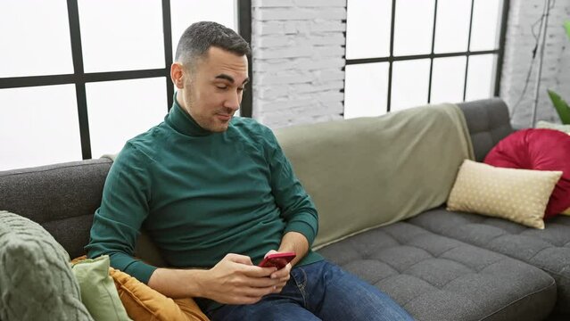 A man and woman enjoying a relaxed moment on a sofa, with the man using a smartphone indoors.