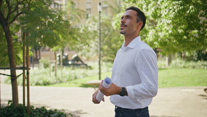 Happy man holding blueprint sunshine greenery park closeup. Hispanic businessman
