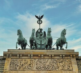 The Quadriga atop the Brandenburg Gate in Berlin is a famous landmark and symbol of the city. - obrazy, fototapety, plakaty
