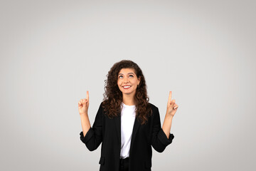 Smiling woman pointing upwards with both hands