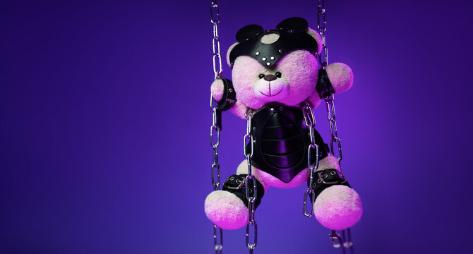 A teddy bear in a mask is suspended from chains in leather handcuffs and accessories for bdsm games and sex in neon light against a background of copy paste