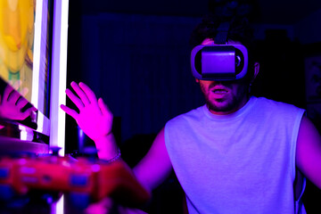 Gesture of surprise and fascination of a man using virtual reality goggles to play online video...