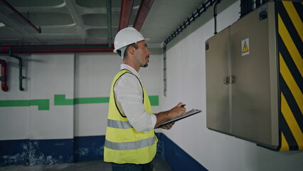 Wiring expert examining power transformer indoors closeup. Serious man writing