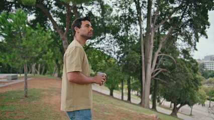 Resting tourist drinking coffee takeaway in beautiful green town garden close up
