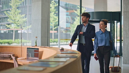 Happy guests arriving hotel carrying luggage. Late receptionist welcome couple