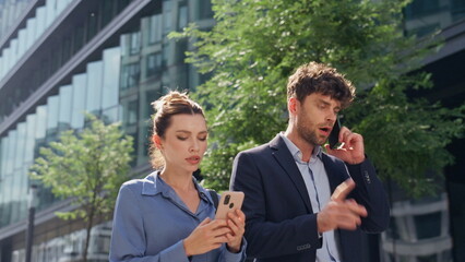 Worried businessman talking smartphone on street. Nervous team walking downtown
