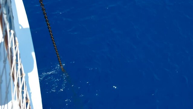 Drop anchor into turquoise sea. A view of droped anchor from the boat into the blue calm sea water in the sun light.