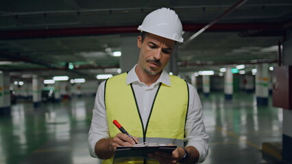 Serious builder filing documents parking portrait. Man in vest looking camera