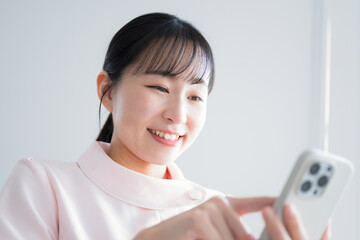 笑顔でスマホを操作する若い女性のイメージ　転職や採用にも