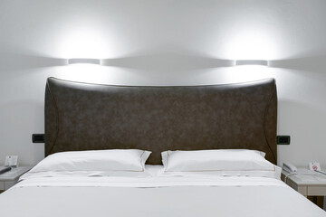 Minimal double bed with white mattress in luxury hotel bedroom. Comfortable bed and pillows indoors.