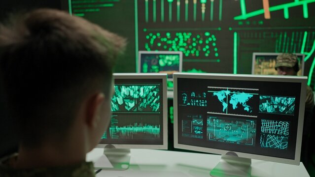 Person security squad in control center. Military headquarters surveillance officer cyber police working in office, tracking and managing security, back shot.