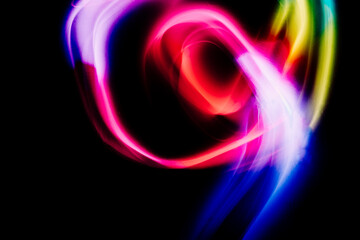 Abstract colorful irregular lines on black background and wall texture. Long exposure. Light painting photography.