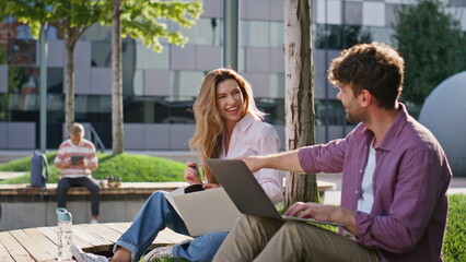 Friends laughing urban park closeup. Smiling couple working remotely chatting