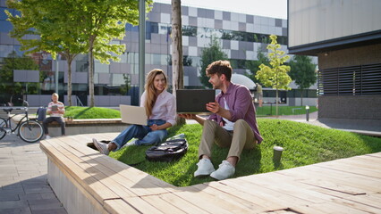 Freelancer team working park together. Smiling couple browsing laptop computer