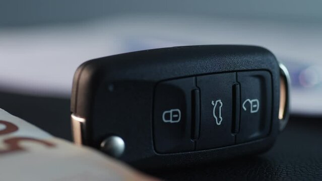 Car Key in focus with money and signed documents blurred in the background.