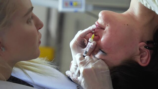Vertical shot of Beautician doctor makes botox injection in the lips of young beautiful woman. Extreme close up 4k shot