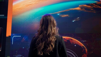 Earth control center, team monitoring galaxy on big screen. Group of people in mission center working on computers, observing discussing flight and space data.