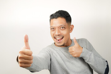 Cute happy face of handsome Asian man with thumbs up, steady expression