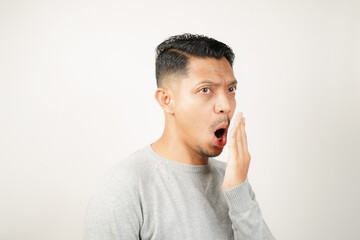 Funny facial expression bad breath with hand covering mouth of Asian man