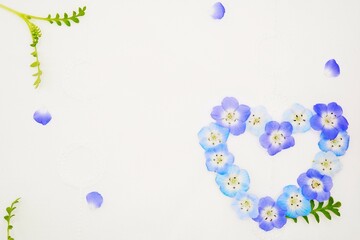 布地の白背景に青く綺麗なネモフィラの花と葉で作った可愛いハートの形の背景素材