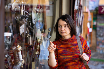 Woman choosing old-fashioned swords in souvenir shop. Toledo, Spain. - 769230555
