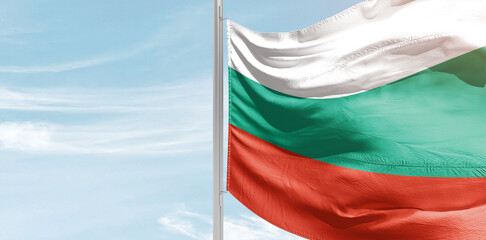 Bulgaria national flag with mast at light blue sky.