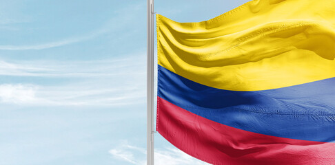Colombia national flag with mast at light blue sky.