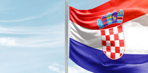 Croatia national flag with mast at light blue sky.