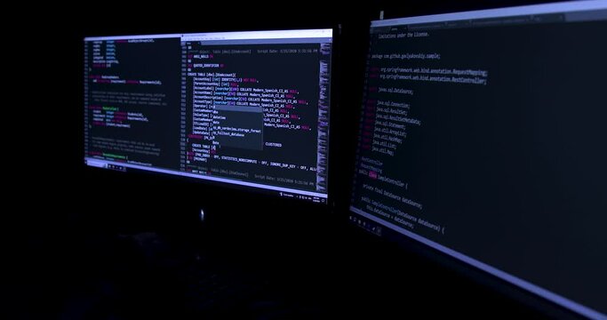 Two computer monitors displaying lines of code. Developer writing code