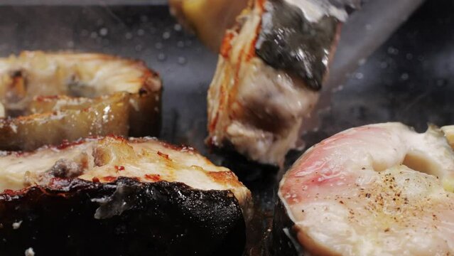 Cooking fillet sturgeon fish on grill or frying pan with oil close-up. Roast healthy food concept. Fry sturgeon, hake, cod fish steak pieces fillet with spice. Healthy diet food