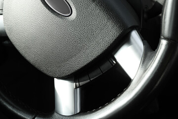 Black steering wheel as background, closeup view