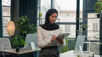 Happy muslim Islam woman Arabian girl in hijab HR manager secretary with paper tablet write notes...