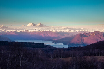 Sunset in the snowed mountains, white clouds on the lake. Swiss Alps and Lake Maggiore seen from Mottarone mountain (Stresa side). Piedmont - Italy.