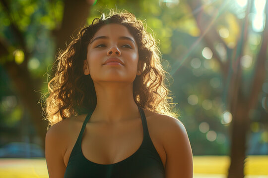 Lifestyle photograph of curly-haired Latin woman exercising in the park during a sunny afternoon