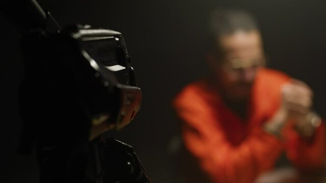 police gesturing to a camera in front of inmate