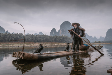 Cormorant fisherman and his birds on the Li River in Yangshuo, Guangxi, China. - obrazy, fototapety, plakaty