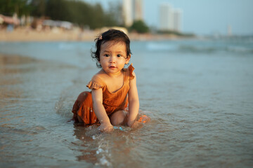 happy toddler baby girl playing toy and water on sea beach