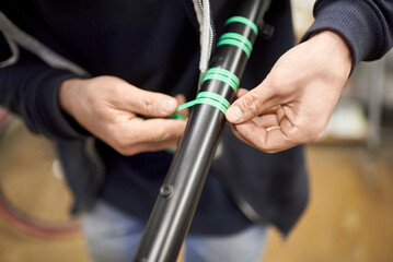 Unknown person preparing a bicycle frame with masking tape for a custom painting design in his bike workshop, a handcrafted creative process.
