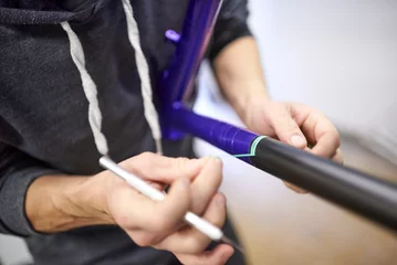 Cercles muraux Moto Unrecognizable person working on a custom bike frame painting design in purple and black, a creative and technical handcrafted process. Time to remove the masking tape.