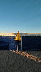 Yellow umbrella closed over beach tents during the golden hour in Pinamar, Buenos Aires, Argentina. 