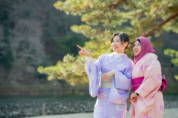 Travel, muslim travel, Arashiyama, woman girl tourist Two Asian friends but different religions in traditional japanese kimonos walking and travel   to Tenryu-ji temple, Kyoto, Arashiyama, Japan.