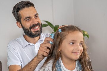 Cute dad brushing the hair of his daughter at home