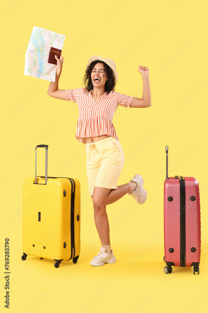 Poster Cheerful African-American female tourist with suitcases and map on yellow background