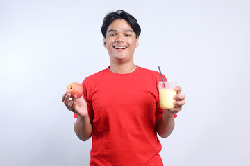 Asian man holding apple fruit and apple juice in plastic cup with paper straw. Healthy food concept