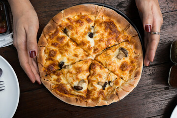 Mushroom pizza with a thin, chewy on woman hand. Top view